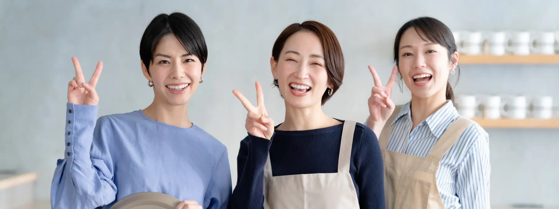 レストランで働く3人の女性が笑顔でピースしている画像