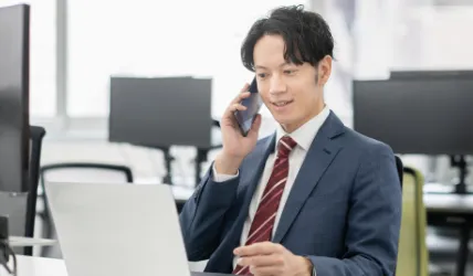 スーツ姿の男性がスマートフォンで電話している画像